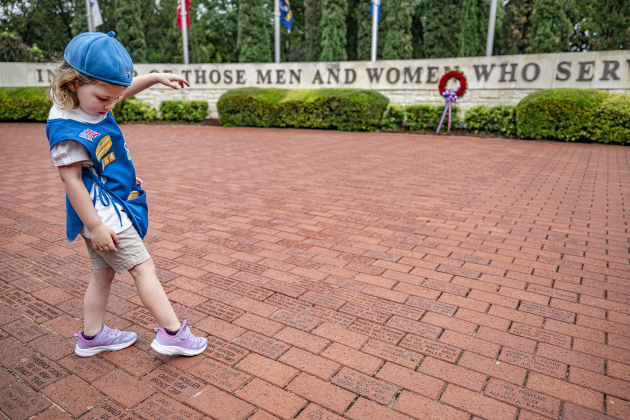 5-year-old Daisy Girl Scout Sawyer Briggs, with Girl Scout Troop 254, spends time in Veterans Memorial Plaza,  finding the commemorative brick honoring her great-grandfather, Mike Harner, who was a Naval aviator in 1960s Vietnam, after  the Memorial Day ceremony in Sun City on Monday, May 26, 2025.  Approximately 600 were in attendance.  Rain chances moved the event indoors, but a few attendees went outside after the ceremony, when rain had stopped.   Photo by Andy Sharp.