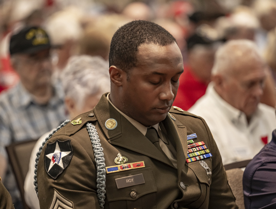 Army Sgt. Craig Roy, with the 3rd Cavalry Regiment Rifle Honor Guard, bows his head during the invocation at  the Memorial Day ceremony in Sun City on Monday, May 26, 2025.  Approximately 600 were in attendance.  Rain chances moved the event indoors.   Photo by Andy Sharp.