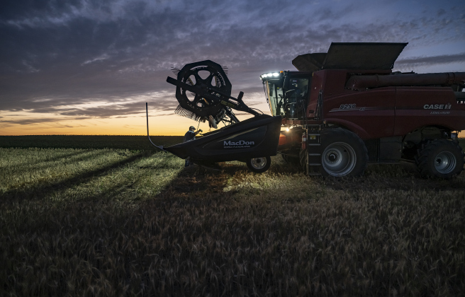 Kyle Kokel, standing at left, works to free up wheat lodged in a combine during Aaron MartinaÕs wheat harvest on Tuesday, May 20, 2025.  Martinka is getting harvest help from friends Larry Svehlak and Kyle Kokel.   Martinka and his helpers are harvesting 700 acres of wheat this season.   Photo by Andy Sharp.  