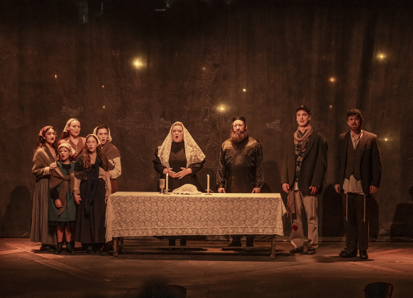 Annie Fizzell, behind table at left, as Golde, and Brian Joyce, behind table at right, as Tevye, are  shown with fellow cast members in a photo from the dress rehearsal for the Palace production of “Fiddler on the Roof”  on Thursday, May 29, 2025.  The play will run through July 6th on the Springer main stage.    Photo by Andy Sharp.