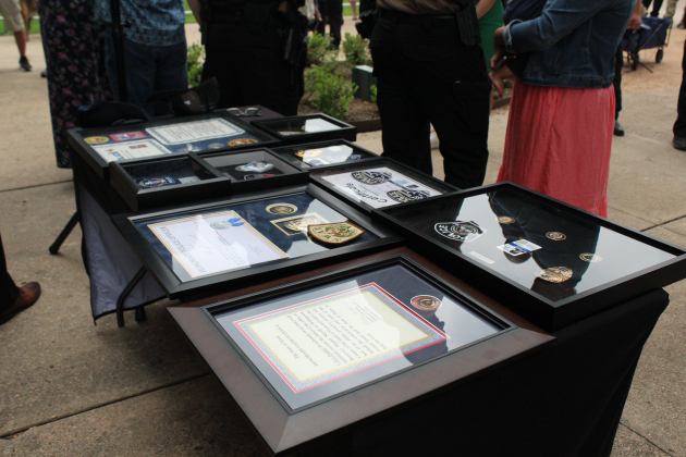 Plaques from nine different law enforcement agencies for DJ decorate a table.