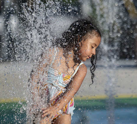4-year-old Anahi Fuentes finds comfort from the heat during a visit to the splash pad at Heritage Square Park.