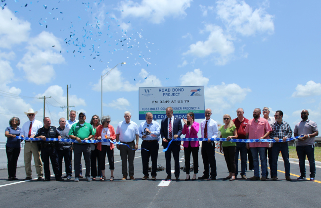 In center U.S. Rep. Pete Sessions, 17th District; Russ Boles, Williamson County commissioner, Precinct 4; Steve Snell, Williamson County judge; Caroline Harris Davila, state representative and Marc Williams, executive director of TxDOT cut the ribbon to open the East Wilco Highway, June 20. Photo by Nalani Nuylan.