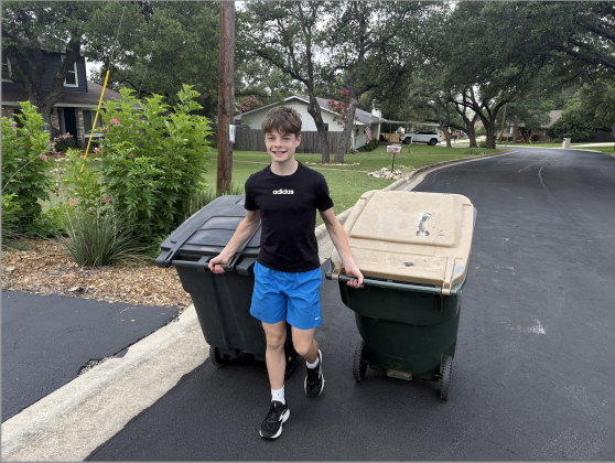 Eli Davis putting out the trash and recycling cans of a Curb Champ customer.