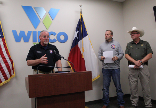 Bruce Clements, from Wilco’s Office of Emergency Management (left), explains plans about how crews will conduct the damage assessment during an 11 a.m. press conference Monday, July 7. County Judge Steve Snell, center, and Sheriff Matt Lindemann, right, listen to the report. Photo by Nalani Nuylan.