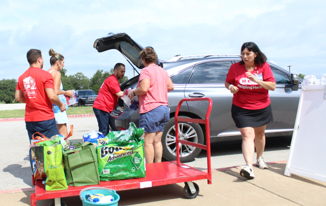 Liberty Hill volunteers are joined by H-E-B helpers to load a flood victim’s car with supplies at a makeshift disaster relief center in Liberty Hill Middle School. Photo by Nalani Nuylan.