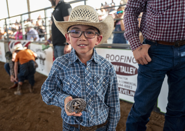 7-year-old Boone Reinke proudly shows off  the belt buckle he won in Mutton Bustin’ at the  75th Annual Taylor Rodeo on Thursday, July 17,2025.  Coordinated by the Taylor Rodeo Association, the three-night rodeo is held at the Williamson County Expo Center.   Photo by Andy Sharp.