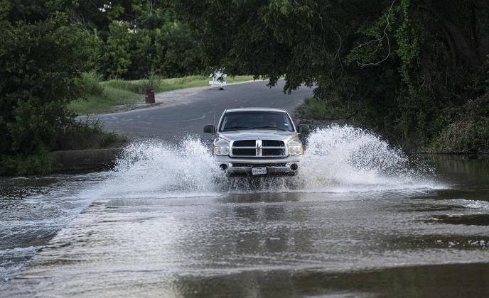 A truck drives through water flowing over the bridge  at Mankins Crossing along the San Gabriel River on Tuesday, July 22, 2025. Recent flooding has made some areas difficult to access.  Signs on either side of the bridge urged drivers to use caution.   Photo by Andy Sharp.