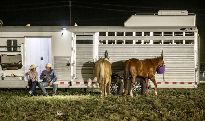 Carsyn Woods of Alice, Texas, left, who competed in Breakaway Roping, relaxes and visits with her dad, Chip Woods, as their horses, Berlin and Playboy, enjoy a snack at right  after all the events were concluded at the Williamson County Sheriff’s Posse Rodeo.