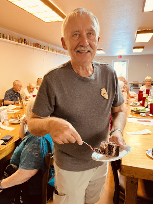 Chicago Club president Jim Bonk grabs a slice of chocolate cake to celebrate Pope Leo XIV. Photo by Linda Dwyer
