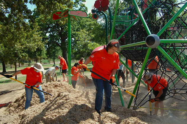 Rhonda Aleman, center, helps fix the playscape at San Gabriel Park by spreading around a cushy wood chip that minimizes impact if children fall on it. (Photo by Kaitlyn Wilkes)