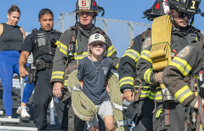 :10-year-old Read Lockwood (carrying hose) walked with his father, Georgetown Fire Department Captain Trey Lockwood (behind Read) during the Memorial Stair Climb held at Birkelbach Field  on Thursday, September 11, 2025 to commemorate  the 24th anniversary of the attacks on United States soil on September 11, 2001.