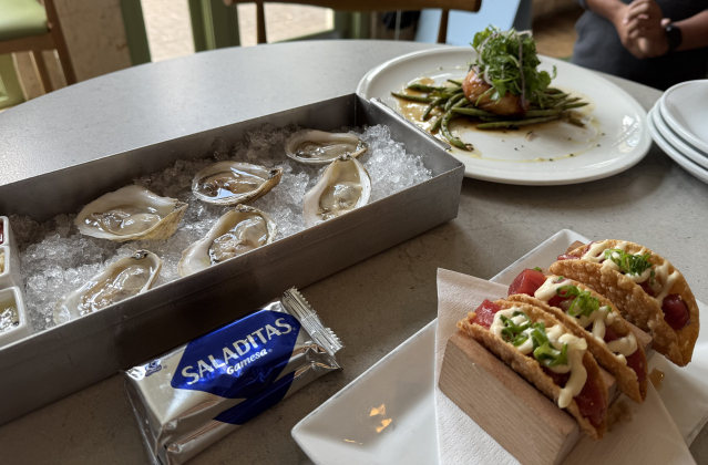 A table of oysters, tuna poke tacos, and sake-roasted sea bass with green beans at Georgie’s.