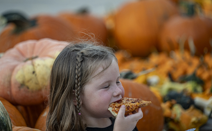 4-year-old Kennedy Cavness relaxes with a well-earned slice of pizza after helping unload more than 3,000 pumpkins at Georgetown First United Methodist Church on Wednesday afternoon, October 8, 2025.