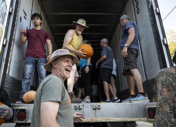Reverend Alan McGrath (front), Senior Pastor, was on hand to help unload more than 3,000 pumpkins at Georgetown First United Methodist Church on Wednesday afternoon, October 8, 2025.  Church members and volunteers from area high schools, plus students from Southwestern University helped  place the pumpkins.  46,000 pounds of pumpkins arrived here from the Navajo Nation in New Mexico.  The pumpkins will be available until Halloween.   Photo by Andy Sharp.