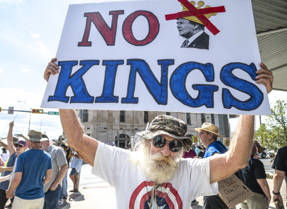 Tom Cooper displays his sign during a “No Kings” demonstration in downtown Taylor on on Saturday afternoon,  October 18, 2025. The crowd was approximately 300, mostly gathered at 2nd and Main Streets.  Photo by Andy Sharp.