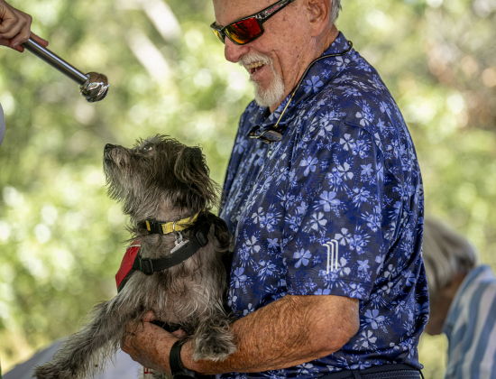 The Reverend Mary Ann Huston, Associate Rector, bestows a blessing on Bogie, with his owner Jess Lofgreen during a Blessing of the Animals service conducted by Grace Episcopal Church, held at Booty’s Road Park on Sunday, October 5, 2025.  Lunch was provided at the park’s pavilion after the service acknowledging the work of Saint Francis of Assisi.   Photo by Andy Sharp.  