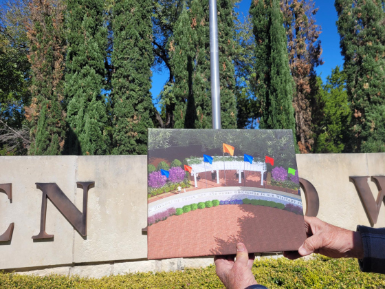 A rendering of what the Veterans Memorial will look like is held up by Tom McCabe against its current state in the background. Photo by Nalani Nuylan.