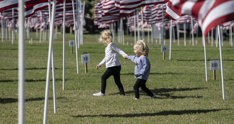 Caroline Baer, 3 (in white top) and her sister Kate, 1, enjoyed running under some of the 2000 American flags at the Georgetown Field of Honor on Sunday, November 9, 2025.