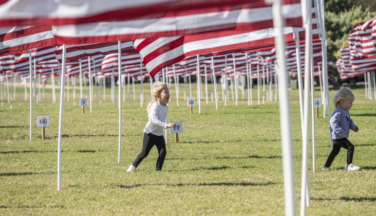 Caroline Baer, 3 (in white top) and her sister Kate, 1, enjoyed running under some of the 2000 American flags at the Georgetown Field of Honor on Sunday, November 9, 2025.