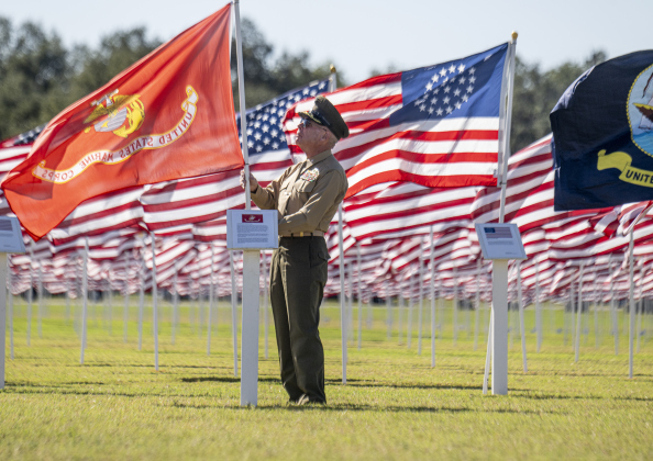 Retired Marine Corps Lt. Colonel Glenn Schneider places the Marine Corps flag during the Parade of Colors  at the Georgetown Field of Honor on Sunday, November 9, 2025.