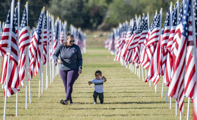 Britney Hollan and her 18-month-old grandson Creed walk through the field of American flags at the Georgetown Field of Honor in San Gabriel Park  on Saturday, November 8, 2025.