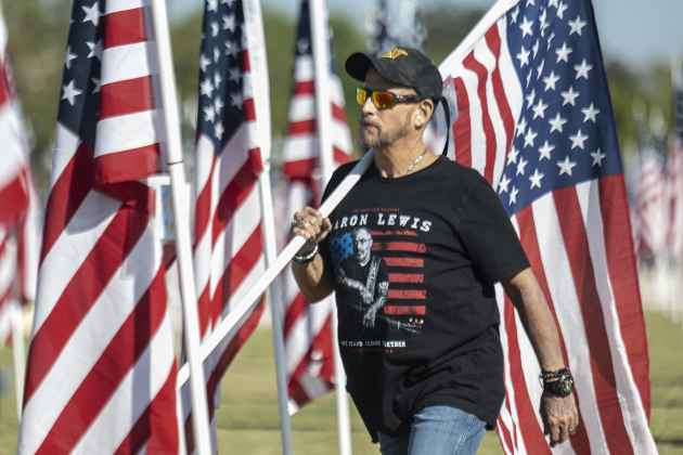 Shawn Downs carries a flag to place in honor of a family member at the Georgetown Field of Honor in San Gabriel Park  on Saturday, November 8, 2025.