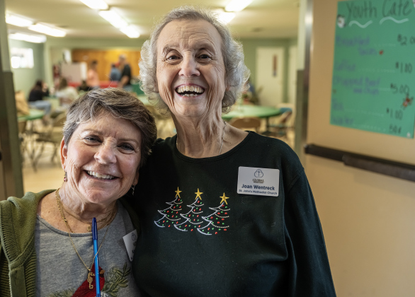 Karen Ruth, left, and Joan Wentrcek were official greeters for visitors attending the 22nd Annual  Come Home for Christmas Celebration held at St. John’s Methodist Church on Saturday, November 22, 2025.  The event included a Youth Cafe, with proceeds going to the St. John’s Youth Ministry.  There was also a silent auction, crafts made by church members, plus a bake sale.   Photo by Andy Sharp.