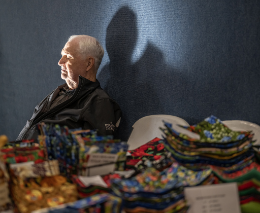 George Miller  enjoys rays of morning light while his wife Mary offers her crafts for sale at the 22nd Annual  Come Home for Christmas Celebration held at St. JohnÕs Methodist Church on Saturday, November 22, 2025.  The event included a Youth Cafe, with proceeds going to the St. JohnÕs Youth Ministry.  There was also a silent auction, crafts made by church members, plus a bake sale.   Photo by Andy Sharp.