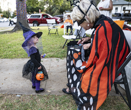 2-year-old Josephine Schlesselman, left, dressed as a witch, visits with Melody Taylor during Halloween along Main Street on Friday, October 31, 2025.  Photo by Andy Sharp.
