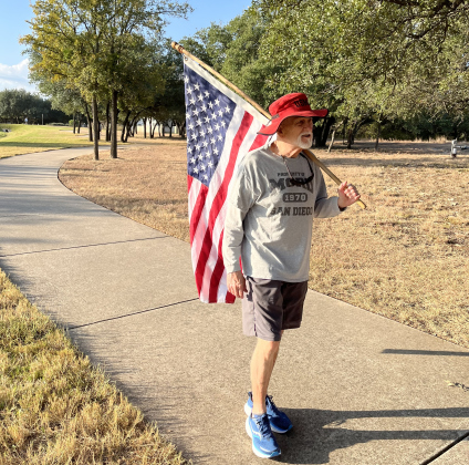 Mike Stankovich walks with an American flag near Sun City Boulevard.