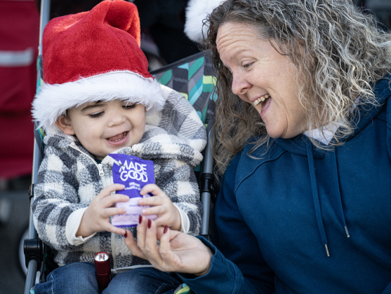 Leo Marin, 2, shares a snack with his grandmother Dodie Marin as they wait for  the parade to start  along Austin Avenue during the annual Christmas Stroll, held in downtown Georgetown on Saturday, December 6, 2025.   Photo by Andy Sharp.