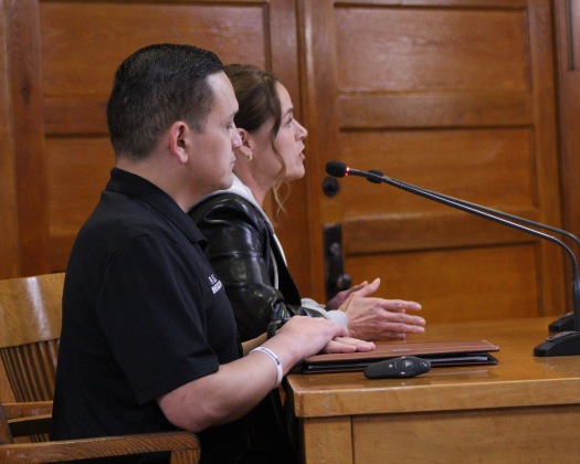 Senior Death Inquest Investigator Ruben Leal, front, joins Justice of the Peace Precinct 2 Angela Williams, back, as she explains the new L.O.S.S program during the December 9 Williamson County Commissioners Court meeting. Photo by Nalani Nuylan