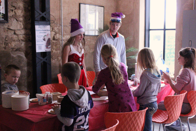 Florence High School seniors Allyson Swanson, left, and Terry Parker, right, help kids decorate cookies for Santa at Dwell Coffee and Tap.