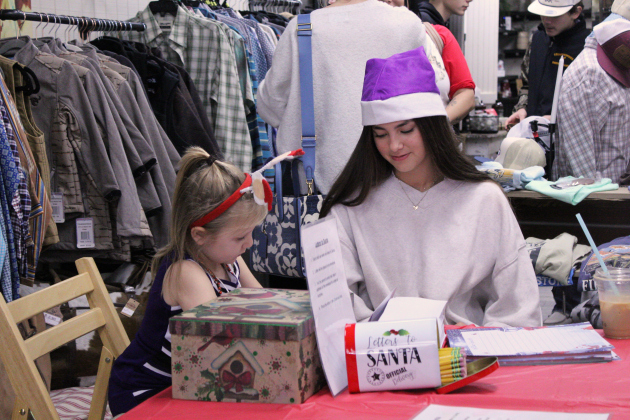 Hunter Swanson, 5, writes a letter to Santa inside the retail shop 205 Mercantile. Florence High School junior Joselyn Preze helps her with spelling.