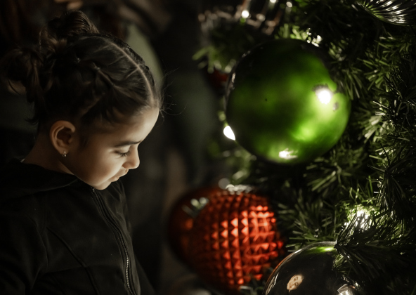 3-year-old Ensley Salais, seeing her reflection in an ornament, enjoys the light from the Christmas tree on the courthouse lawn during the Lighting of the Square on Friday, November 28, 2025.  Photo by Andy Sharp.