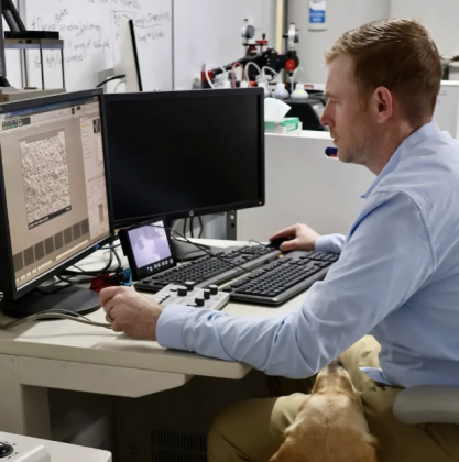 Justin Tullos, owner of Phineas Laboratory, doing work while his service dog Hercules lays on his lap. Photo courtesy of Phineas Laboratory 