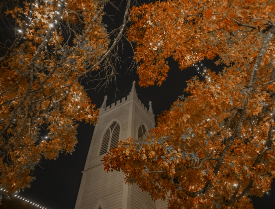 A front portion of Grace Heritage Center is framed by a tree covered with holiday lights  on Tuesday, December 16, 2025.  Photo by Andy Sharp.