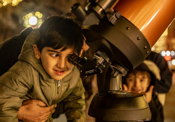 5-year-old Aydin Bajar looks at a Waxing Gibbous moon through a telescope brought to 8th and Main Streets by  Brad Sloan  on Wednesday, December 31, 2025, New Years Eve in Georgetown.   Photo by Andy Sharp.