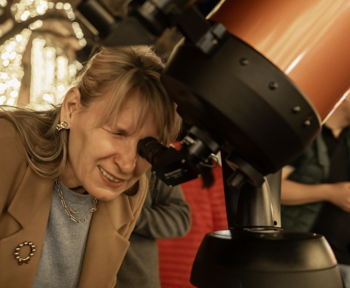Ingrid Pearson looks at the Waxing Gibbous moon through a telescope placed at 8th and Main Streets by  Brad Sloan on Wednesday, December 31, 2025, New Years Eve in Georgetown.   Photo by Andy Sharp.