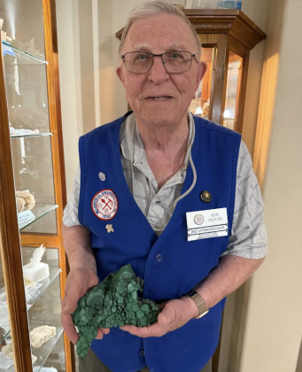 Ken Oliver, Education Ambassador for the Williamson County Gem and Mineral Society, holding malachite in front of his display case. Photo by Abbey Archer