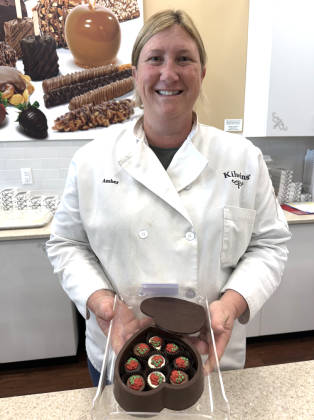 Amber Kurkowski, co-owner of Kilwins in Georgetown, holds a chocolate heart box. Customers have the option of filling the edible chocolate boxes with truffles of their choosing. Photo by Abbey Archer