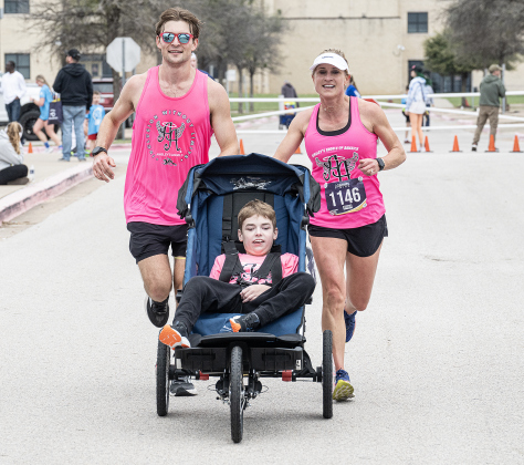 Conor Hamilton, a member of the Ainsley’s Angels team, was assisted by his ambassadors Alec Romick, left, and Daphni Eissing, right, as he took part in the 5K Race during  the annual Chase The Chief races held at East View High School on Sunday, March 8, 2026.