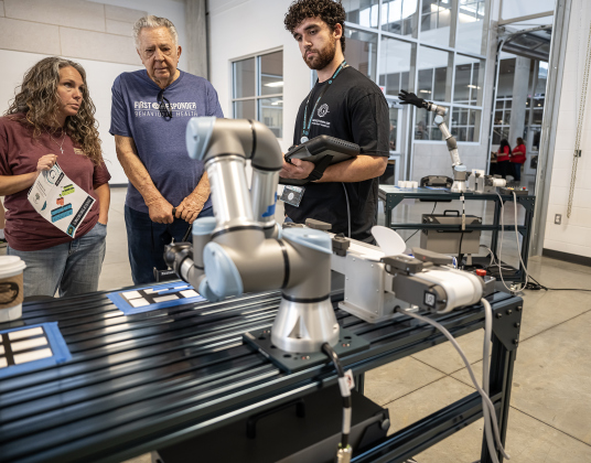 Brooke Flowers and her father Philip Kappler listen to Georgetown High manufacturing class student Aiden Sullivan, a senior, right, explain how he has his robot programmed to take directions  at the Georgetown ISD State of the District gathering held at the Future Ready Complex on Friday, March 6, 2026.