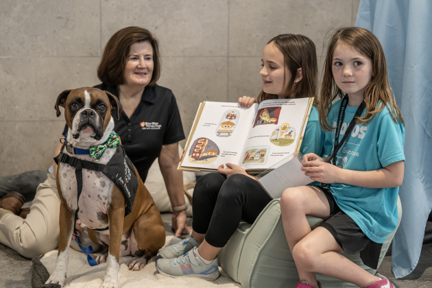 Max, a Therapy Dog with The Dog Alliance, is shown with his owner Kat Boyd at left as they spend time with Frost Elementary School students Tyra Walker, center, a second grader, and Adalyn Chambley, right, a first grader, during the Georgetown ISD State of the District gathering held at the Future Ready Complex on Friday, March 6, 2026.  Max makes regular visits to Frost.   District students and staff were on hand to demonstrate their skills in various areas.
