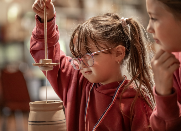 6-year-old Joanna Taylor, left, joined by her sister Delilah, 8, right, had fun learning how to churn butter  at the Old Settlers Association  site during The Williamson Museum’s Hoppy Easter event on Saturday, March 14, 2026.