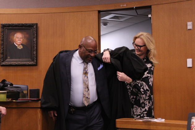 Judge King helps Mr. Miller put on her Judge's robe as friends and coworkers laugh at the sudden playfulness in the 26th district court. The joke was Chief Trailer's idea.