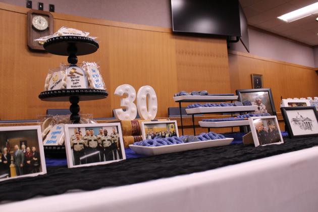 A table filled with desserts is decorated with photos of Mr. Miller's 30 years of service.