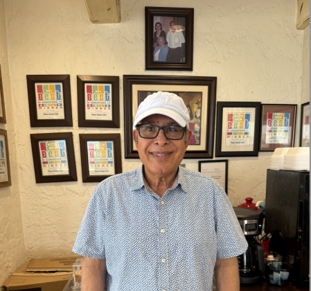 Plaka Greek Cafe Owner Mo Kosari stands in front of an award wall in the restaurant, which has earned many first-place Best of Georgetown Awards in the “Best Ethnic (Non-Mexican/Tex-Mex)” category. Above his head is a photo of George and Zlata Betondo, the restaurant’s original owners, with Lady Bird Johnson. Photo by Abbey Archer