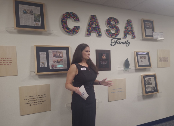 Marissa Austin, CEO of Court Appointed Special Advocates of Williamson County, gives a speech dedicating the room she’s in to Patti Hewlett, who is pictured on the wall, April 1. Photo by Nalani Nuyaln.